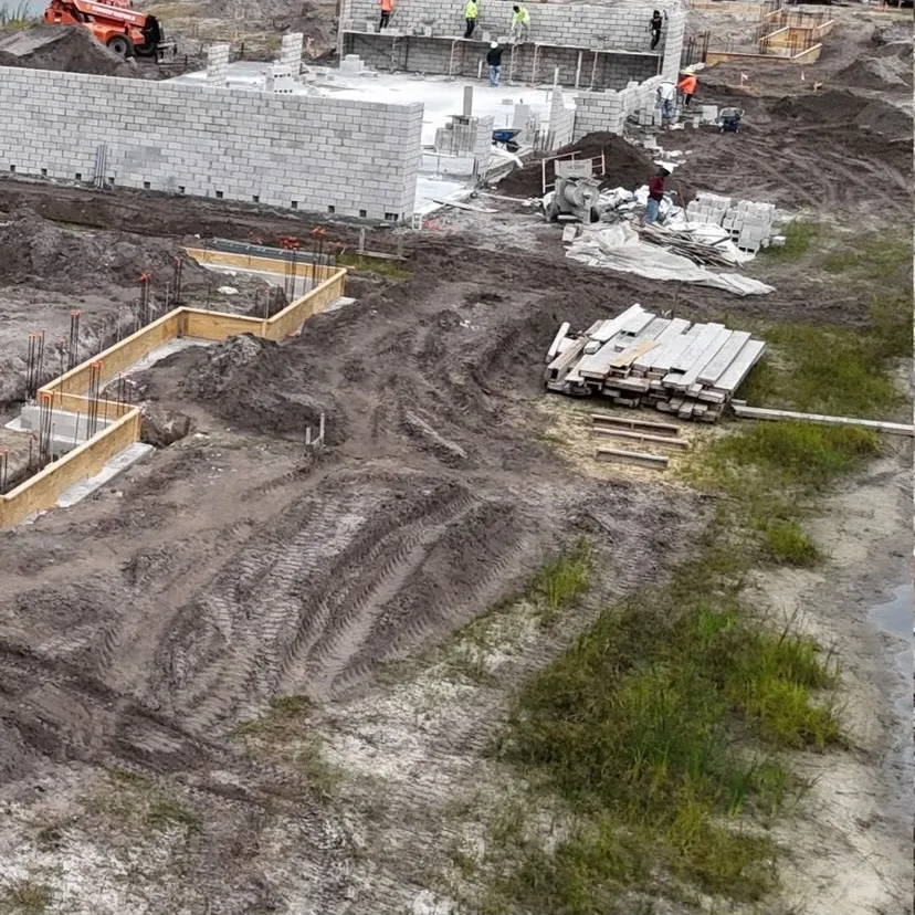Aerial view of block walls going up over a completed plumbing rough-in